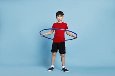 Photo of Boy exercising with hula hoop on light blue background