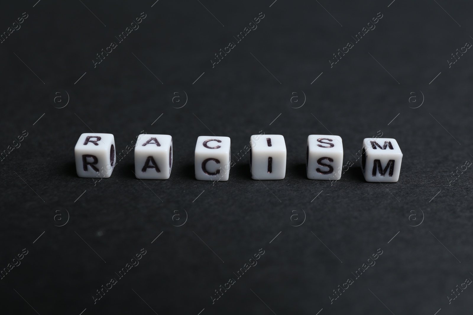 Photo of Word Racism made with beads on black background, closeup