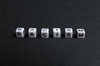 Photo of Word Racism made with beads on black background, closeup