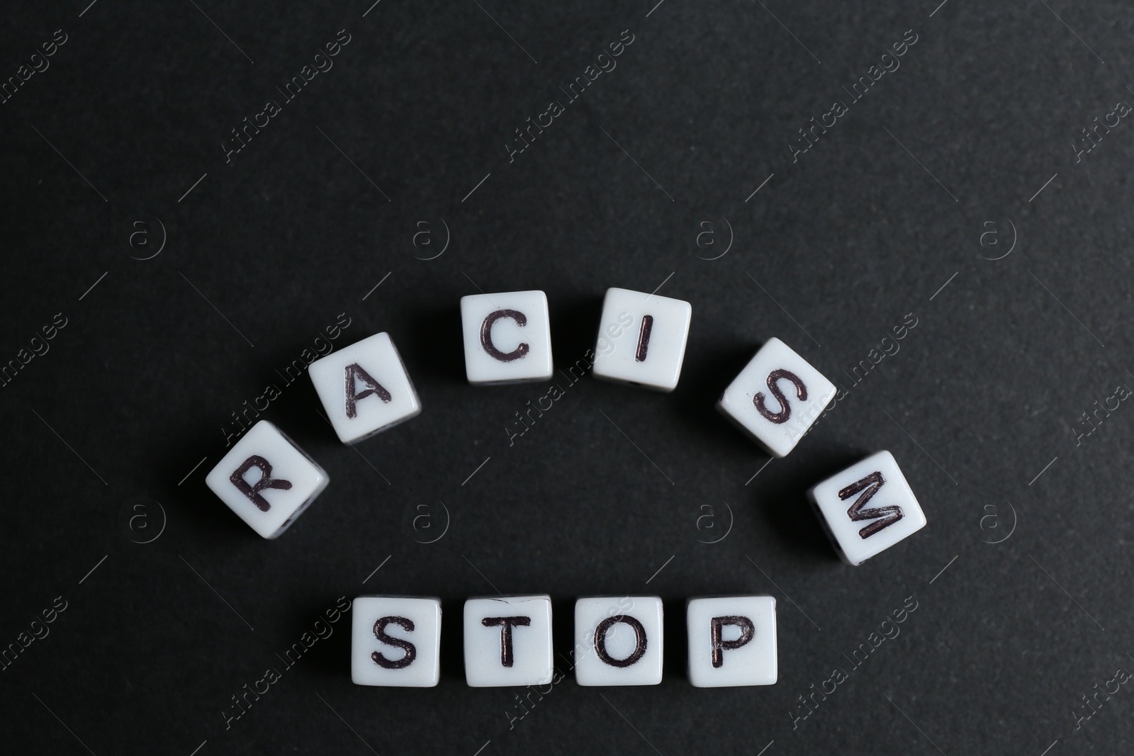 Photo of Phrase Stop Racism made with beads on black background, top view