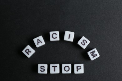 Photo of Phrase Stop Racism made with beads on black background, top view