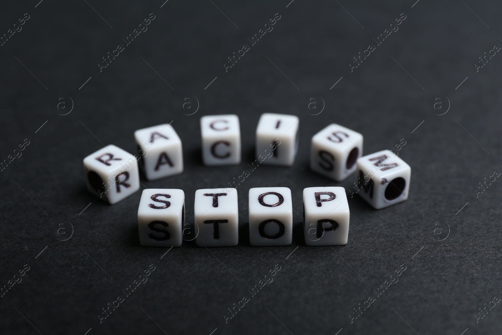 Photo of Phrase Stop Racism made with beads on black background, closeup