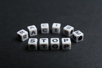 Photo of Phrase Stop Racism made with beads on black background, closeup