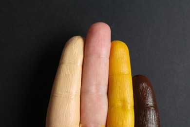 Photo of Stop racism. Woman with her fingers painted in different colors on black background, top view