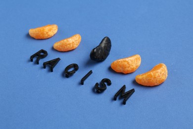 Photo of Word Racism and tangerine segments of different colors on blue background, closeup