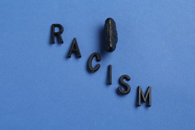 Photo of Word Racism and black tangerine segment on blue background, top view