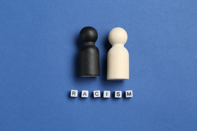 Photo of Word Racism and human figures of different colors on blue background, top view