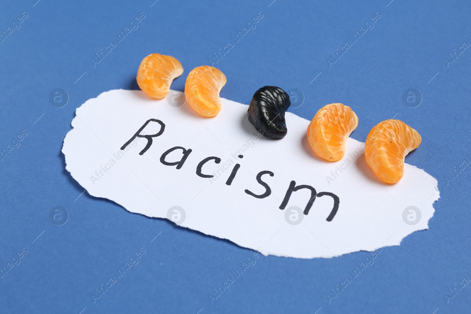 Photo of Card with word Racism and tangerine segments of different colors on blue background