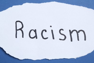 Photo of Card with word Racism on blue background, closeup