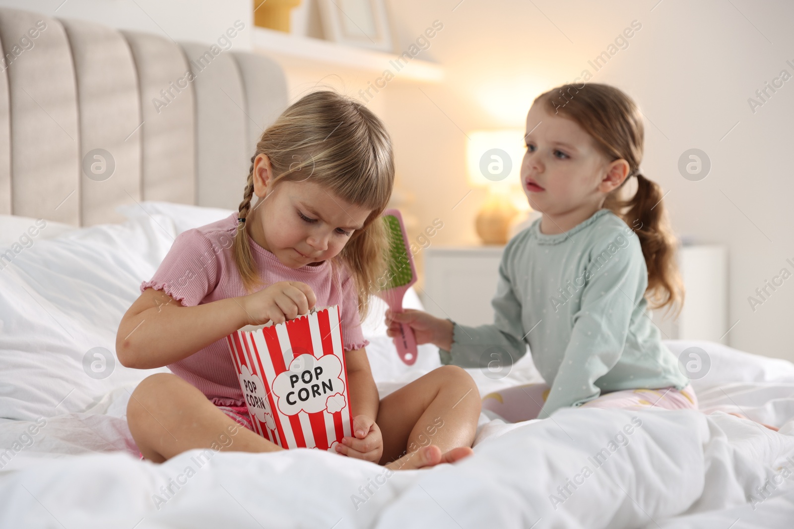 Photo of Cute little sisters spending time together on bed at home, selective focus