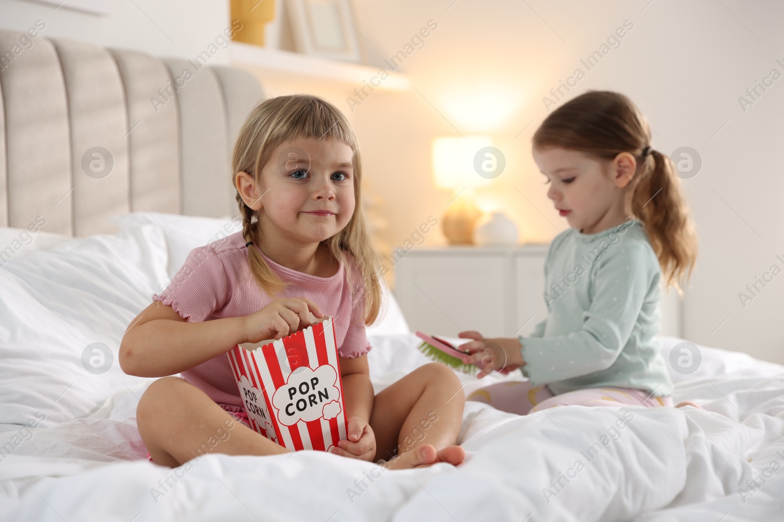 Photo of Cute little sisters spending time together on bed at home, selective focus