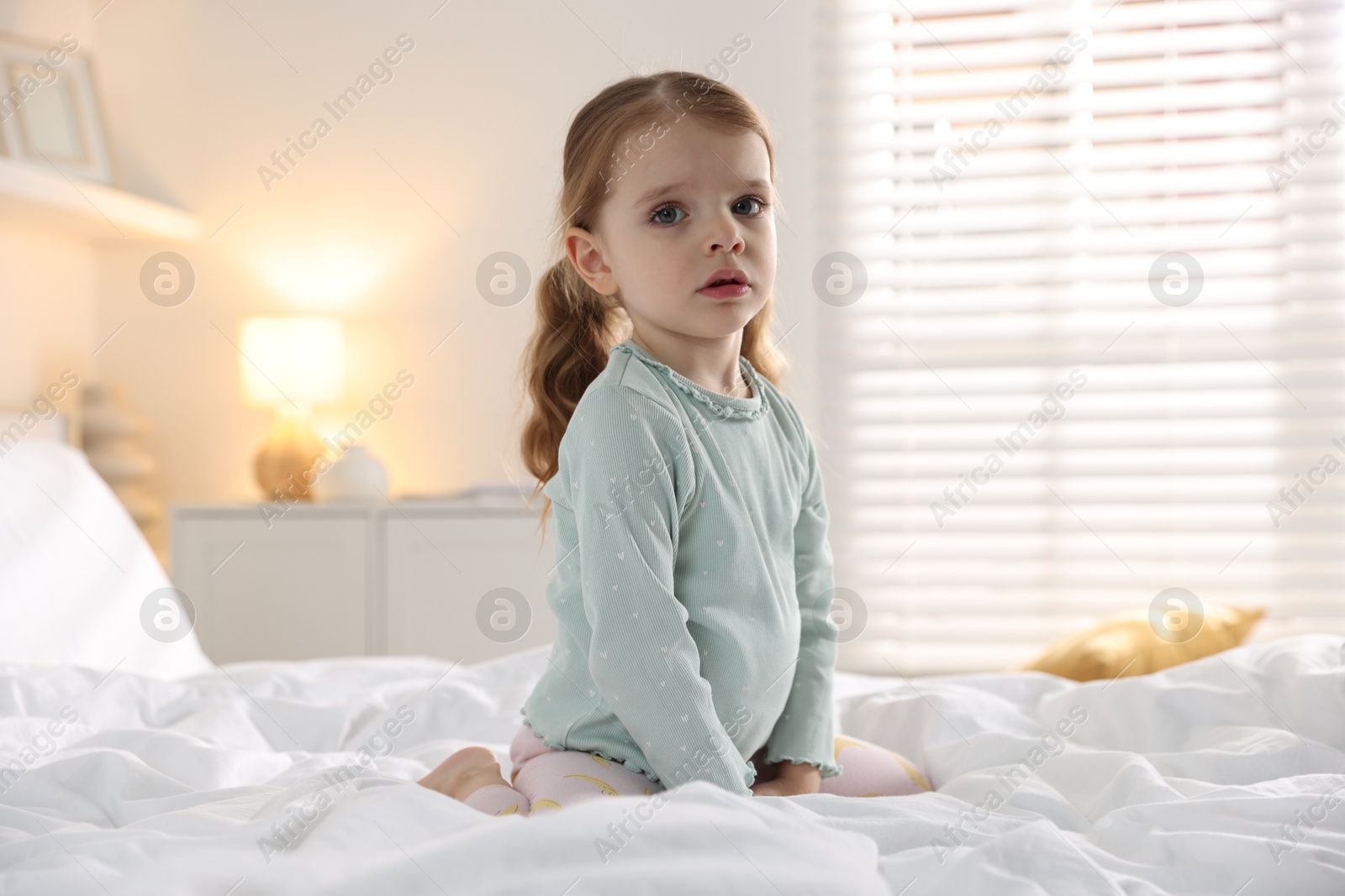 Photo of Cute little girl on bed at home