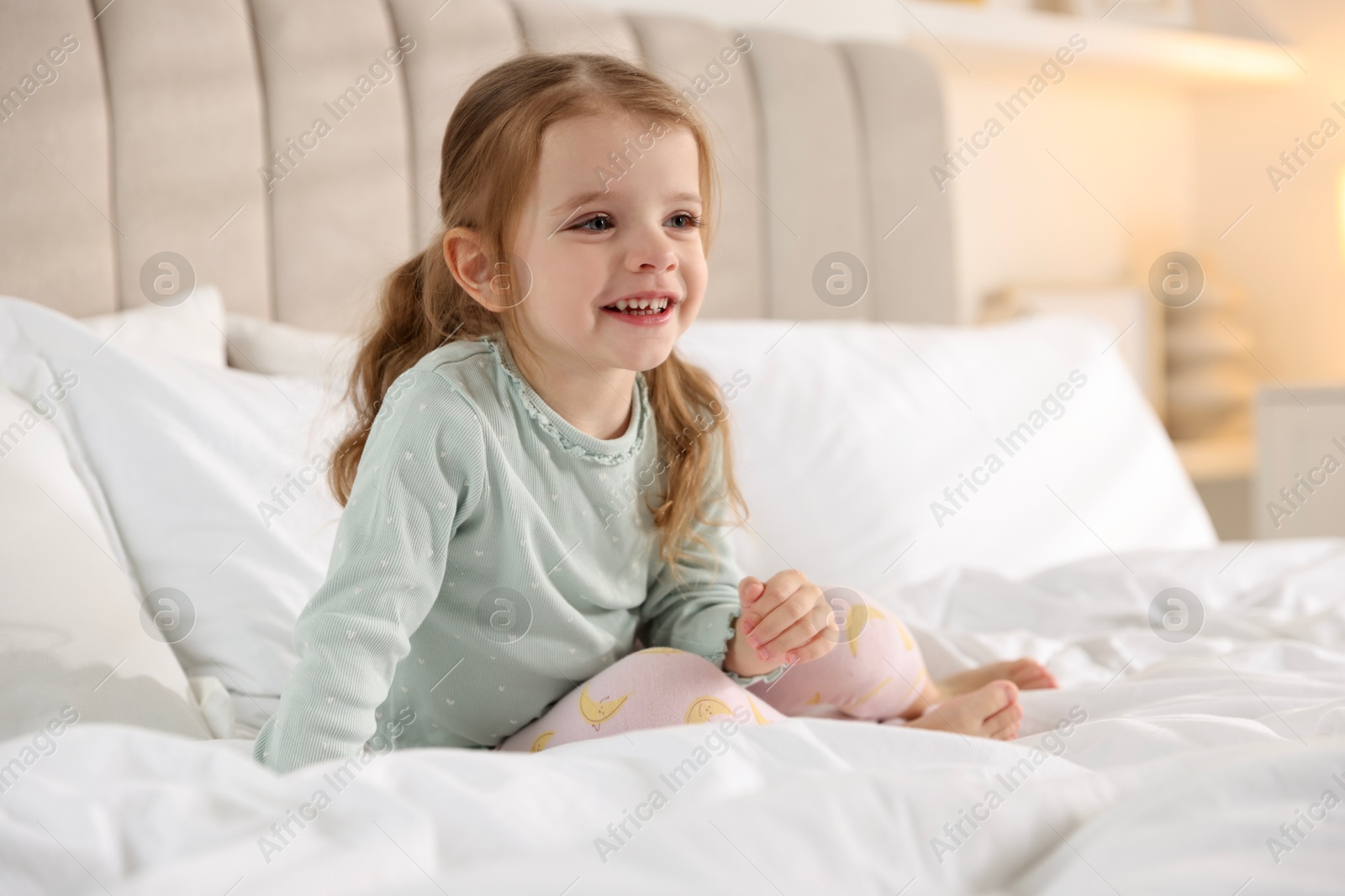 Photo of Cute little girl on bed at home