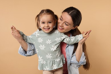 Photo of Portrait of happy mother and her cute little daughter on beige background