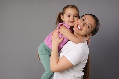 Photo of Portrait of happy mother and her cute little daughter on grey background