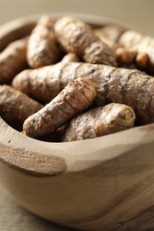 Photo of Raw turmeric roots in bowl on table, closeup