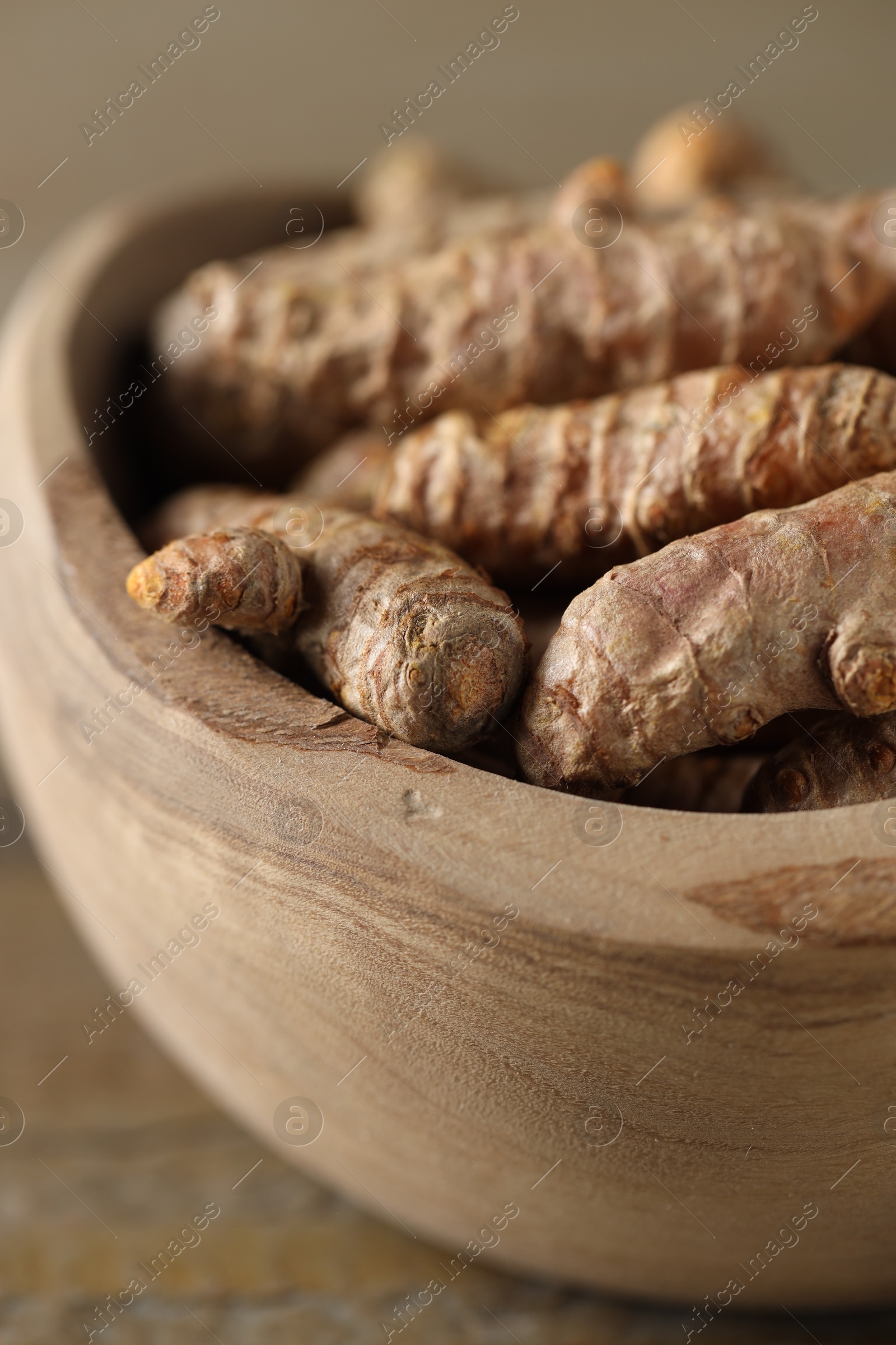 Photo of Raw turmeric roots in bowl on table, closeup