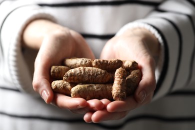 Photo of Woman holding raw turmeric roots, closeup view