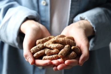 Photo of Woman holding raw turmeric roots, closeup view