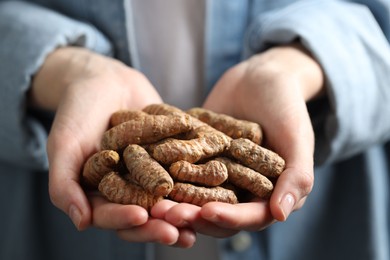 Photo of Woman holding raw turmeric roots, closeup view