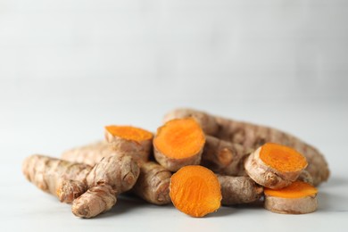 Photo of Pile of raw turmeric roots on white marble table, closeup