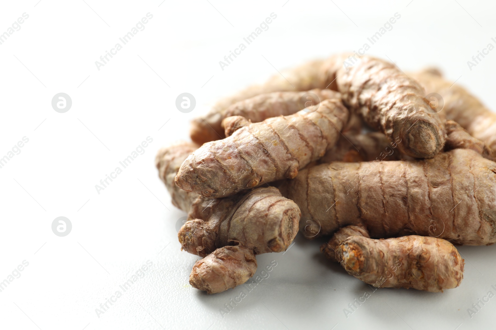 Photo of Pile of raw turmeric roots on white marble table, closeup. Space for text