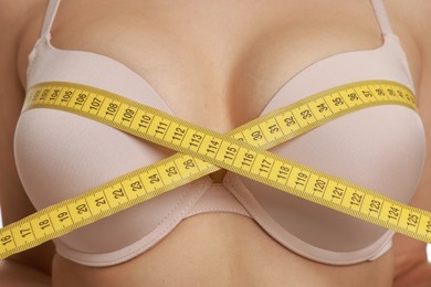 Photo of Woman in beautiful bra measuring breast circumference, closeup