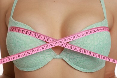 Photo of Woman in beautiful bra measuring breast circumference, closeup