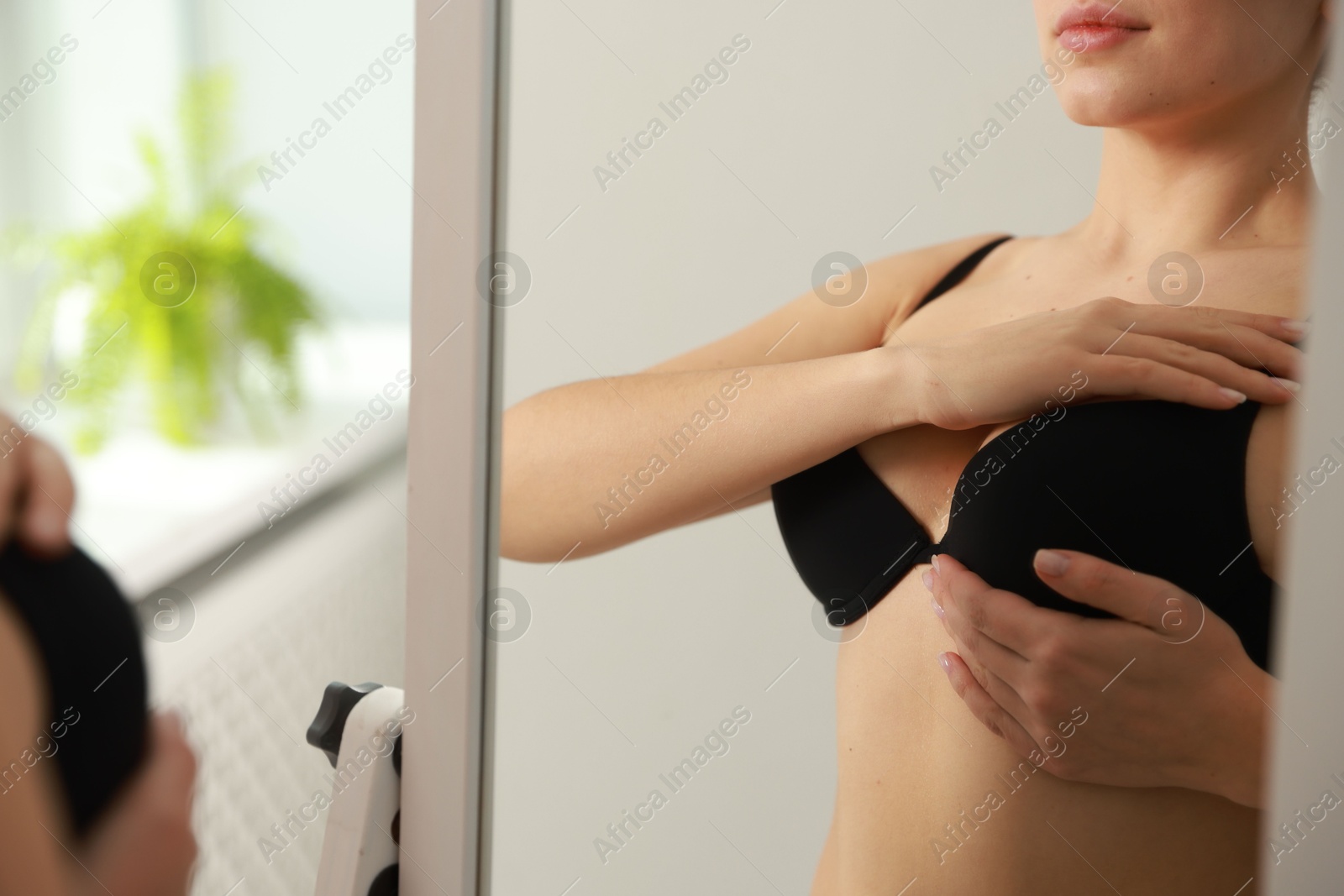 Photo of Woman wearing beautiful bra near mirror indoors, closeup