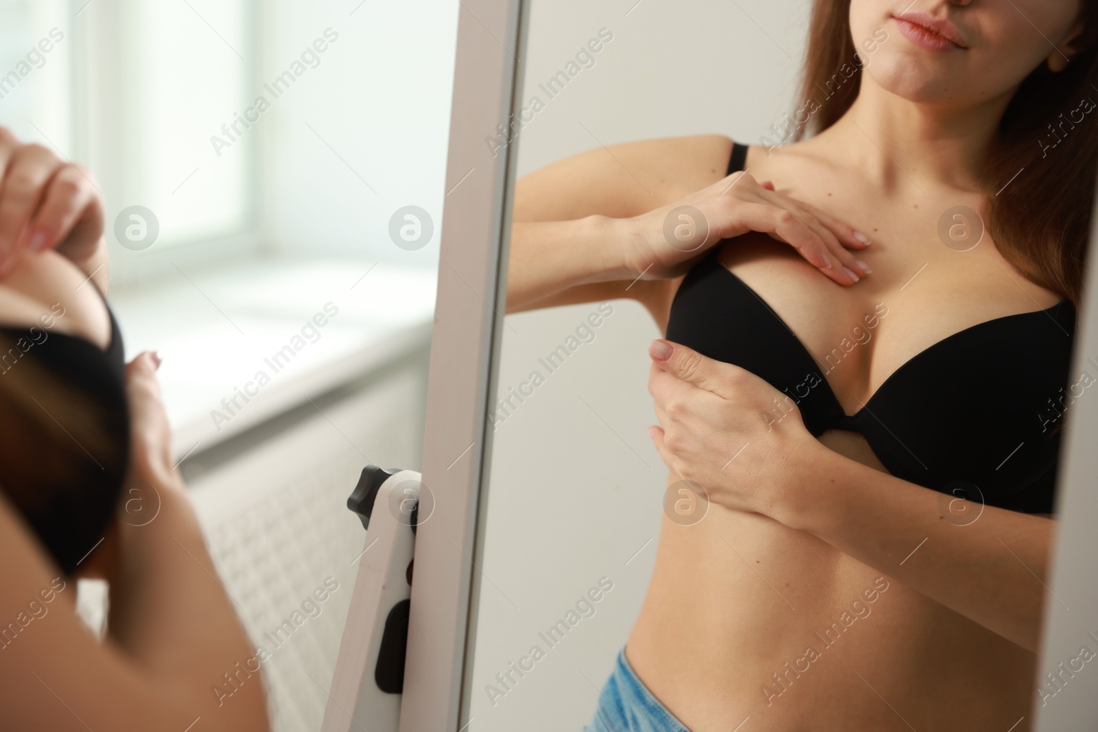 Photo of Woman wearing beautiful bra near mirror indoors, closeup