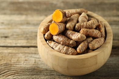 Photo of Tumeric rhizomes in bowl on wooden table, closeup