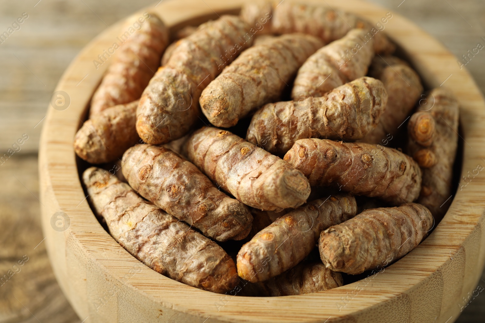 Photo of Tumeric rhizomes in bowl on table, closeup