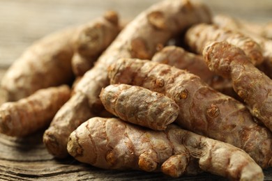 Photo of Pile of tumeric rhizomes on wooden table, closeup