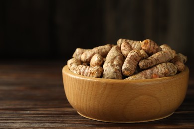 Photo of Tumeric rhizomes in bowl on wooden table, closeup