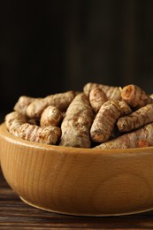 Photo of Tumeric rhizomes in bowl on wooden table, closeup