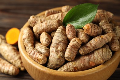 Photo of Tumeric rhizomes with leaf in bowl on table, closeup