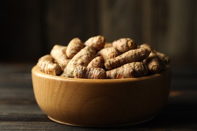 Photo of Tumeric rhizomes in bowl on wooden table, closeup