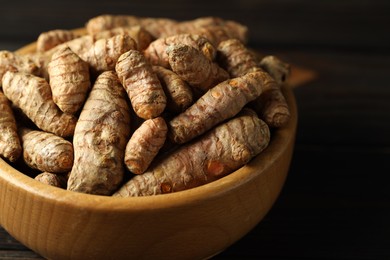 Photo of Tumeric rhizomes in bowl on wooden table, closeup