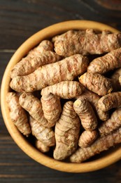 Photo of Tumeric rhizomes in bowl on wooden table, top view