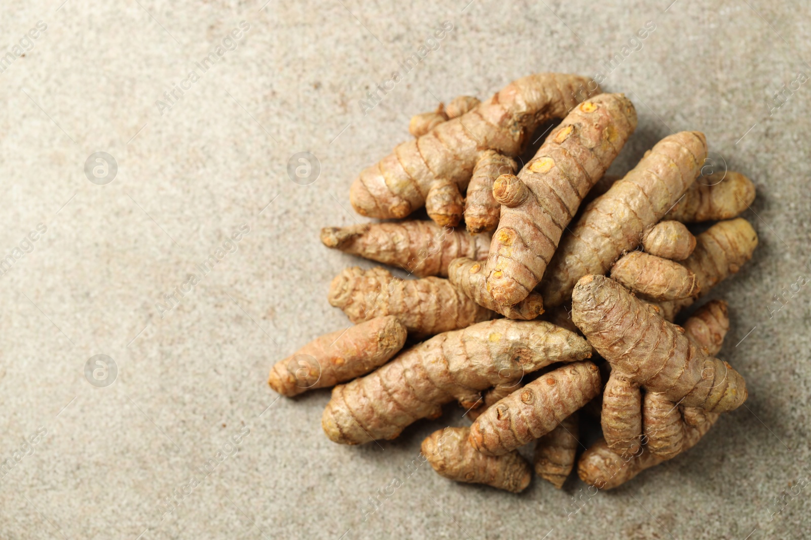 Photo of Pile of tumeric rhizomes on grey table, top view. Space for text