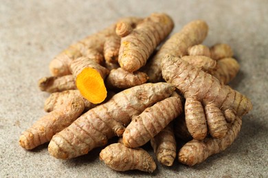 Photo of Pile of tumeric rhizomes on grey table, closeup