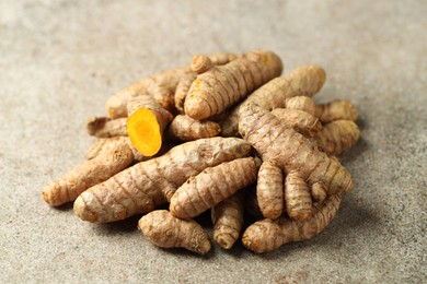 Photo of Pile of tumeric rhizomes on grey table, closeup