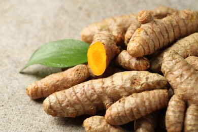 Photo of Pile of tumeric rhizomes with leaf on grey table, closeup