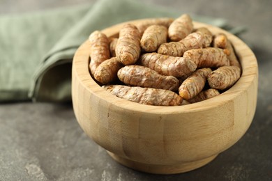 Photo of Tumeric rhizomes in bowl on grey table, closeup