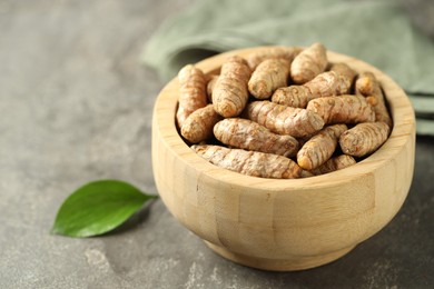 Photo of Tumeric rhizomes in bowl on grey table, closeup