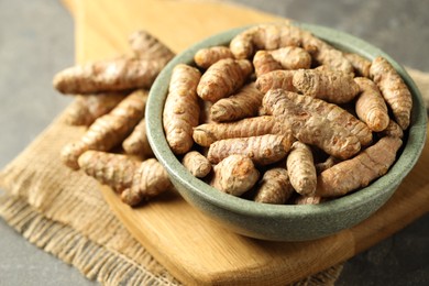 Photo of Tumeric rhizomes in bowl on grey table, closeup