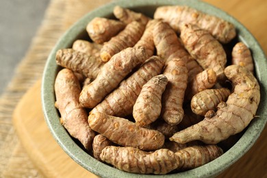 Photo of Tumeric rhizomes in bowl on grey table, closeup