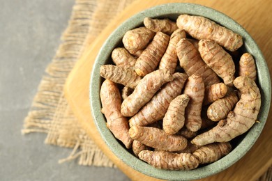 Photo of Tumeric rhizomes in bowl on grey table, top view