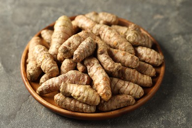 Photo of Raw tumeric rhizomes on grey table, closeup