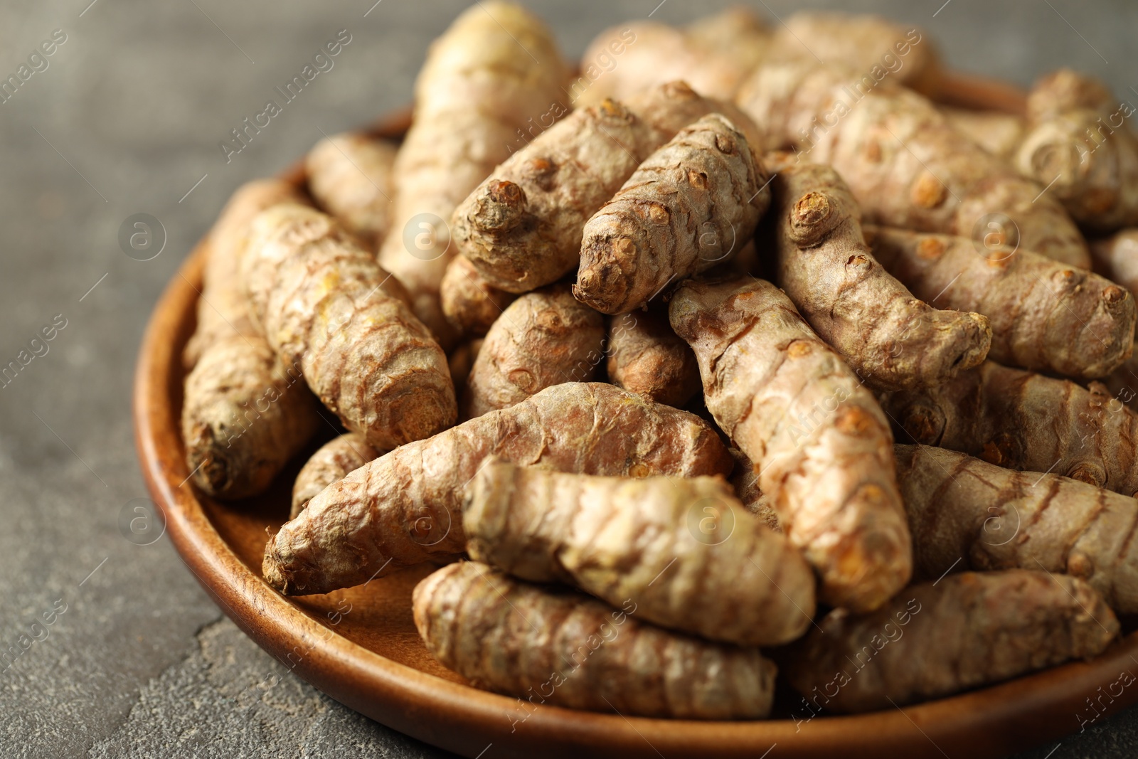 Photo of Raw tumeric rhizomes on grey table, closeup